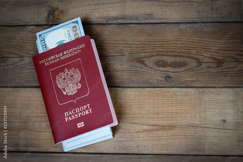 Russian passport with dollars inside on wooden background, concept of immigration Russian passport with dollars inside on wooden background, concept of immigration