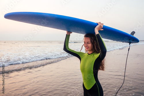 Photography Beautiful woman in a diving suit for swimming surfing in the Indian Ocean on the background sunset sky and waves