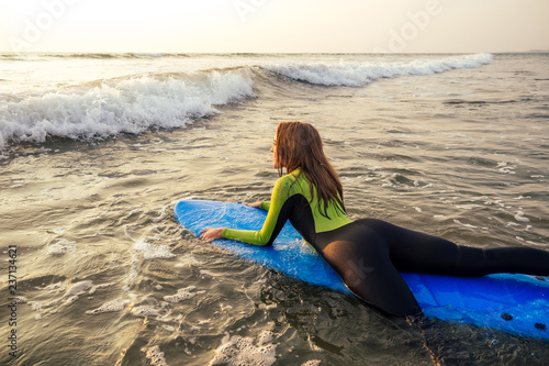 active women with surf board enjoy watersport at vacation holidays.sport girl in surfing school instructor of windsurf. tourist female model in a diving suit wetsuit on the beach in the Indian Ocean