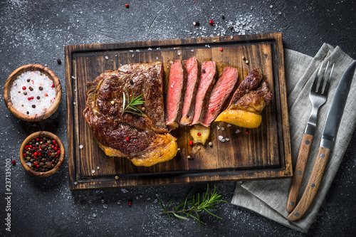 Foto Grilled beef steak ribeye on wooden cutting board.