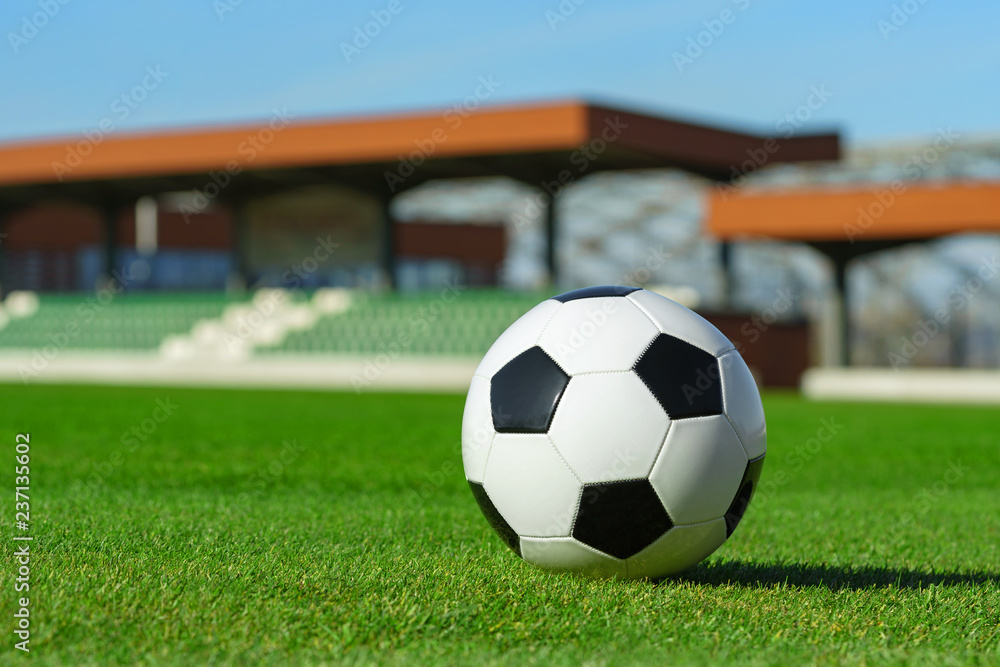 Classic soccer ball lying on the bright green grass on the football