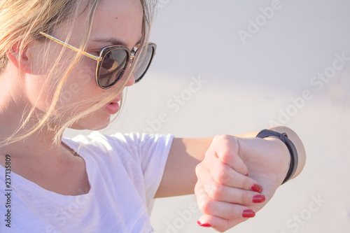 Beautiful sports girl is touching her fitbit bracelet after training.