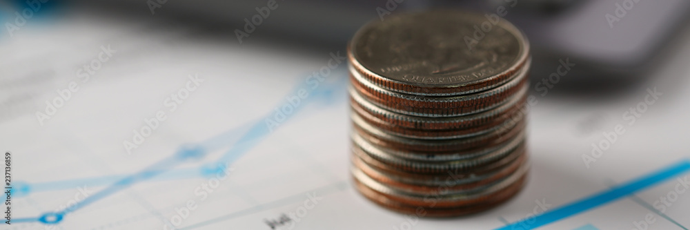 Pile of silver coins stand at financial graph papers Pile of silver coins stand at financial graph papers