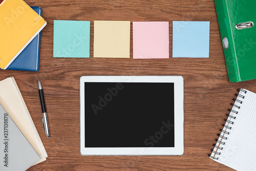 top view of four sticky notes and digital tablet with blank screen on wooden office desk