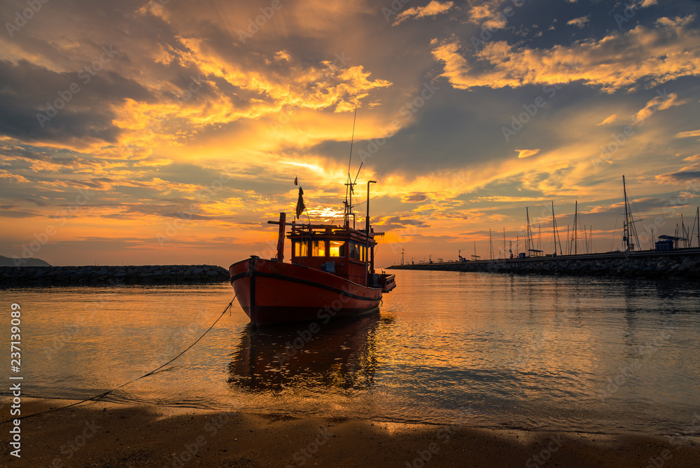 Obraz premium Silhouette fishing boat parking on beach at sunset time sky backgroun