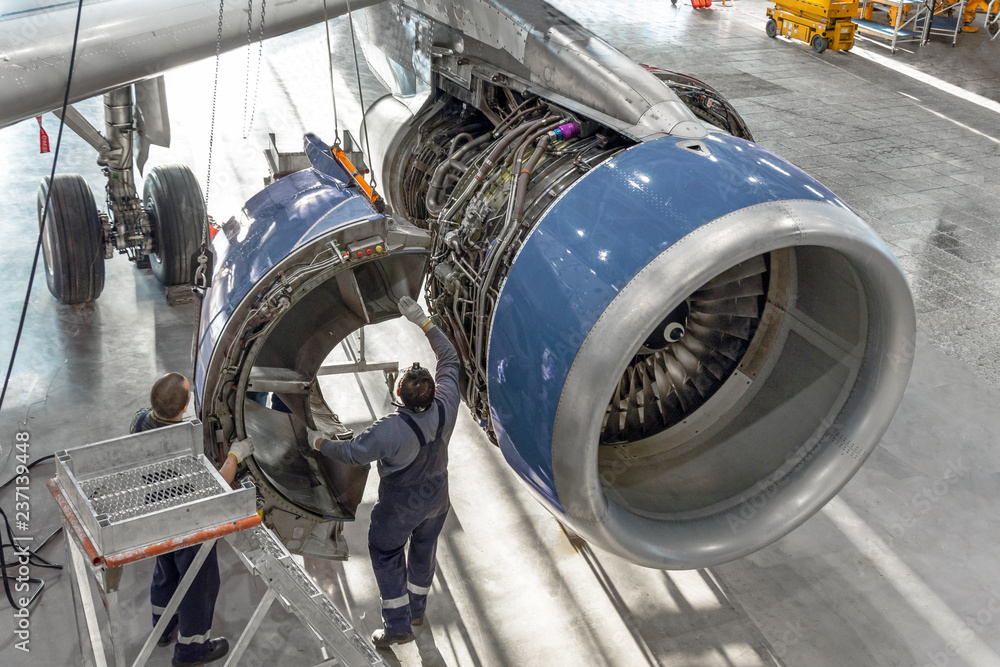 Fototapeta premium Specjaliści techniczni i technicy lotnictwa instalują silnik odwrotny po zaplanowanym serwisie. Konserwacja koncepcji samolotu.