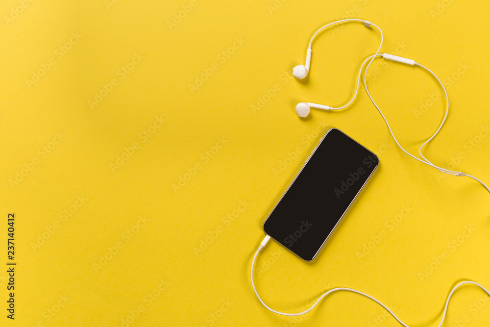 Mobile phone with white earphones on colour backgroung, top view Mobile phone with white earphones on colour backgroung, top view