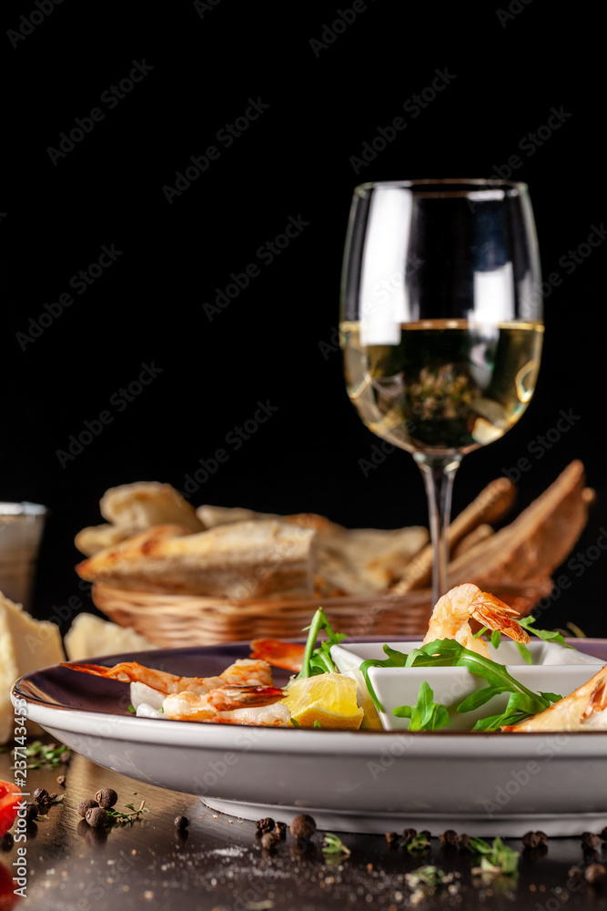The concept of Italian cuisine. Tiger prawns on rice chips in a creamy sauce. Arugula salad and lemon. On the table is a glass of red wine. beautiful serving in the restaurant