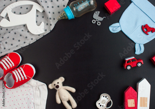 Newborn baby clothing and accessories on black chalk board