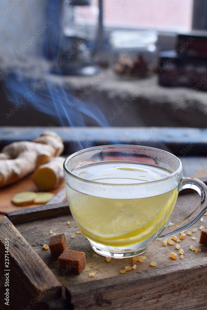 Cup of ginger tea with lemon and brown sugar on wooden backgraund. Hot drink for cough remedy. Traditional medicine and natural health care concept. Copy space for text. Cup of ginger tea with lemon and brown sugar on wooden backgraund. Hot drink for cough remedy. Traditional medicine and natural health care concept. Copy space for text.