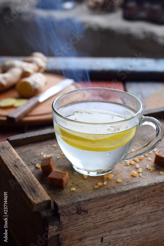 Cup of ginger tea with lemon and brown sugar on wooden backgraund. Hot drink for cough remedy. Traditional medicine and natural health care concept. Copy space for text.