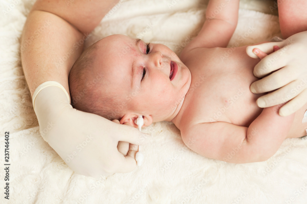 The child at the doctor's office and his ears are cleaned with a cotton swab. The child at the doctor's office and his ears are cleaned with a cotton swab.