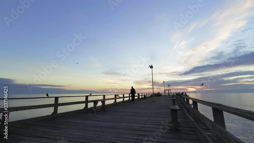 unknown fisherman walking on the pier at sunrise
