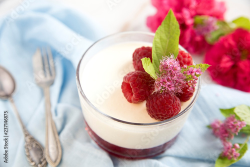 Great panacotta dessert with raspberries, on a blue background and vintage spoon and fork. Retro . photo