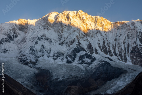 Close-up view of Annapurna 1 summit and glacier against clear blue sky during sunrise ( golden hour) in the Himalayas