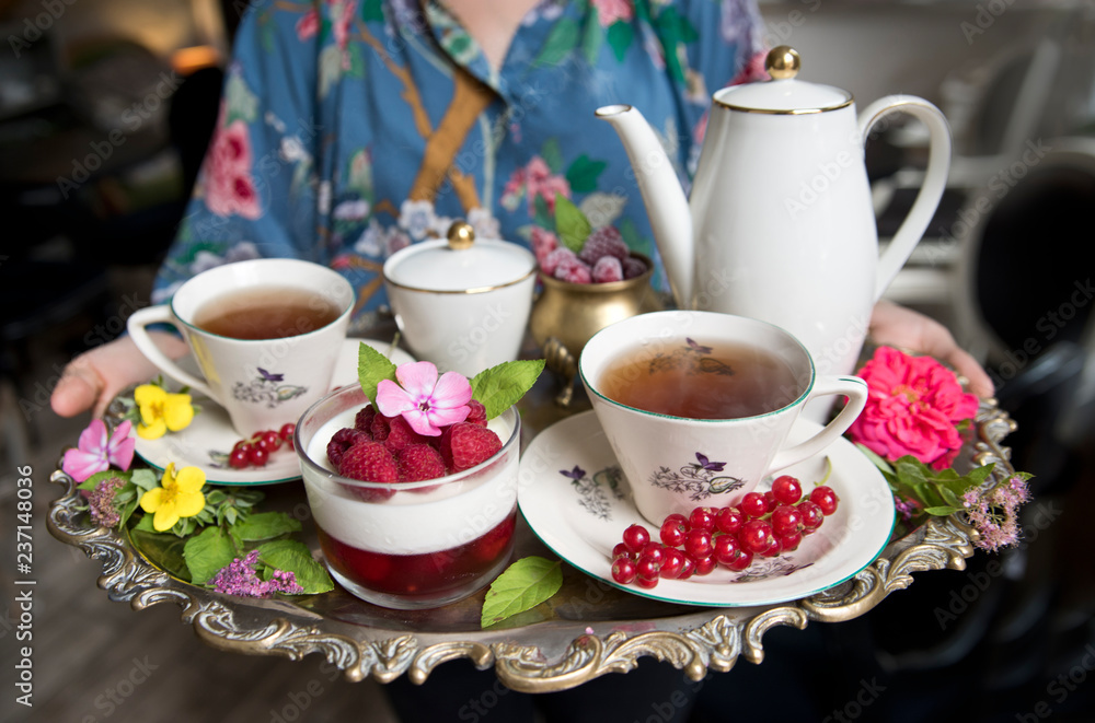 Magnificent fresh hot tea in ancient cups on a silver vintage tray and a raspberries dessert, an antique teapot Magnificent fresh hot tea in ancient cups on a silver vintage tray and a raspberries dessert, an antique teapot