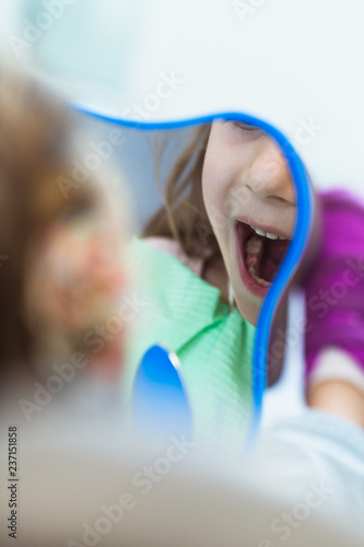 A little girl looks in the mirror after dental treatment