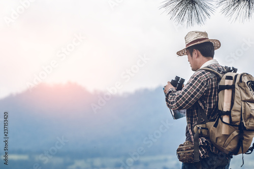 traveler holding binoculars on the mountains with map.
