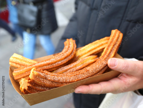 Hand Holding Spanish Churros with Cinnamon and Sugar at Christmas Market Weihnachtsmarkt in Hannover,Germany