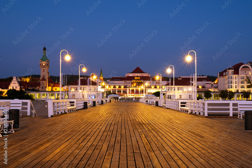 Fototapeta premium Długie drewniane molo w Sopocie z widokiem na latarnię morską