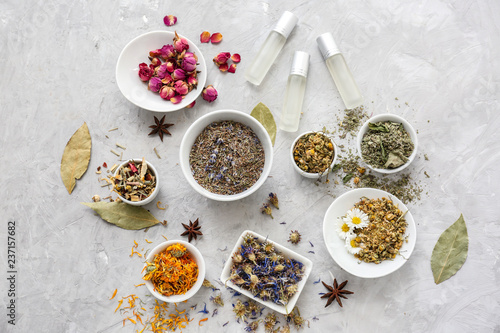 Aromatic dried flowers with herbs and essential oil on grey table