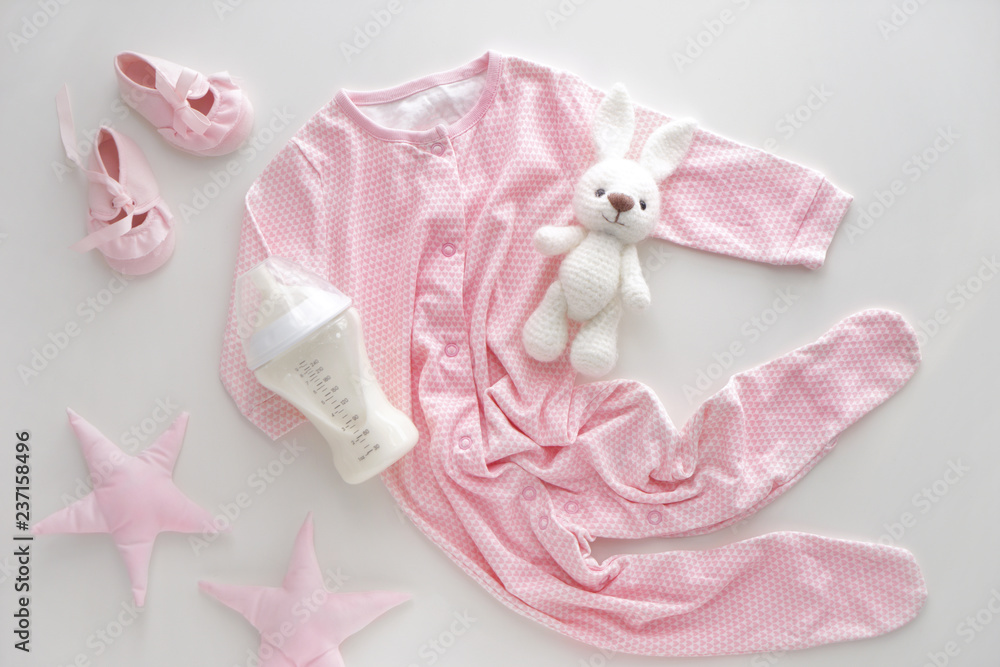Feeding bottle of baby formula with toys and clothes on white background Feeding bottle of baby formula with toys and clothes on white background