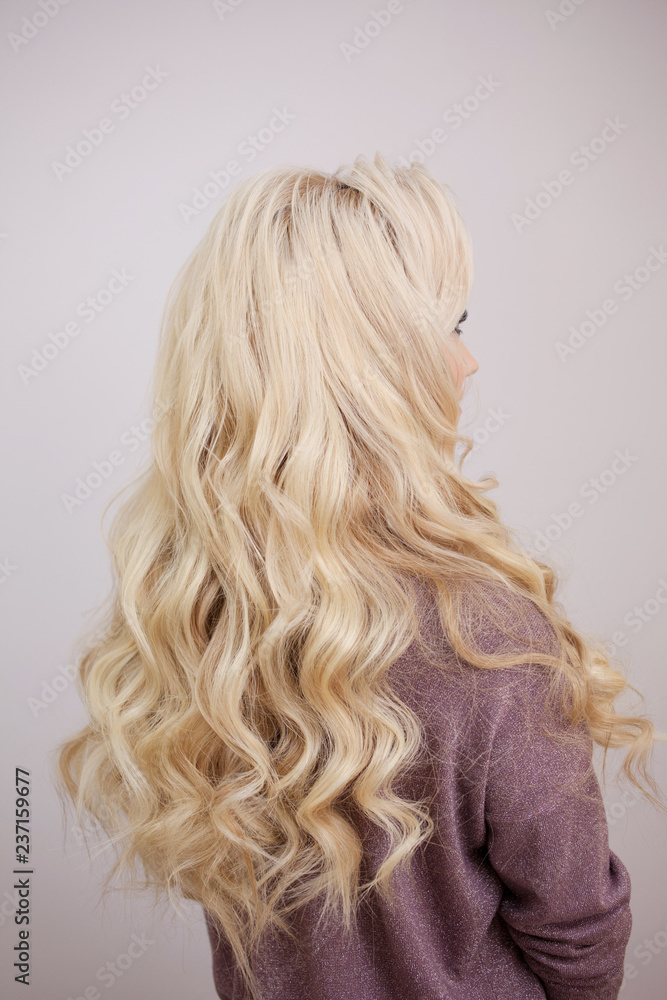 Naklejka premium Back view of blonde with long luxurious curls.