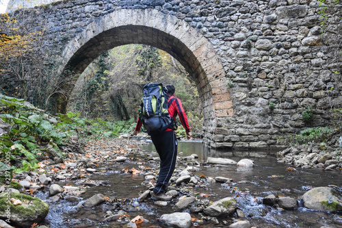 Man In a river under an old bridge. hiker in nature under a bridge in a canyon