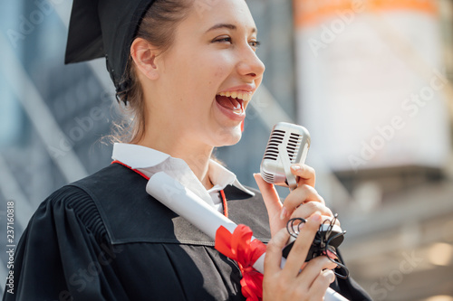 Happy woman on her graduation day University. Education and people.Happy to announce the release of the microphone.