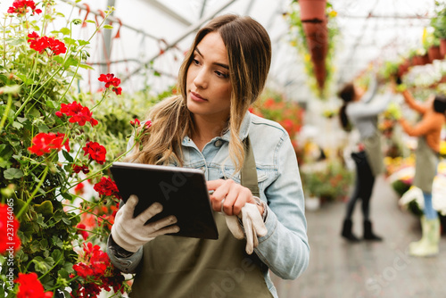 Florist holding digital tablet in greenhouse