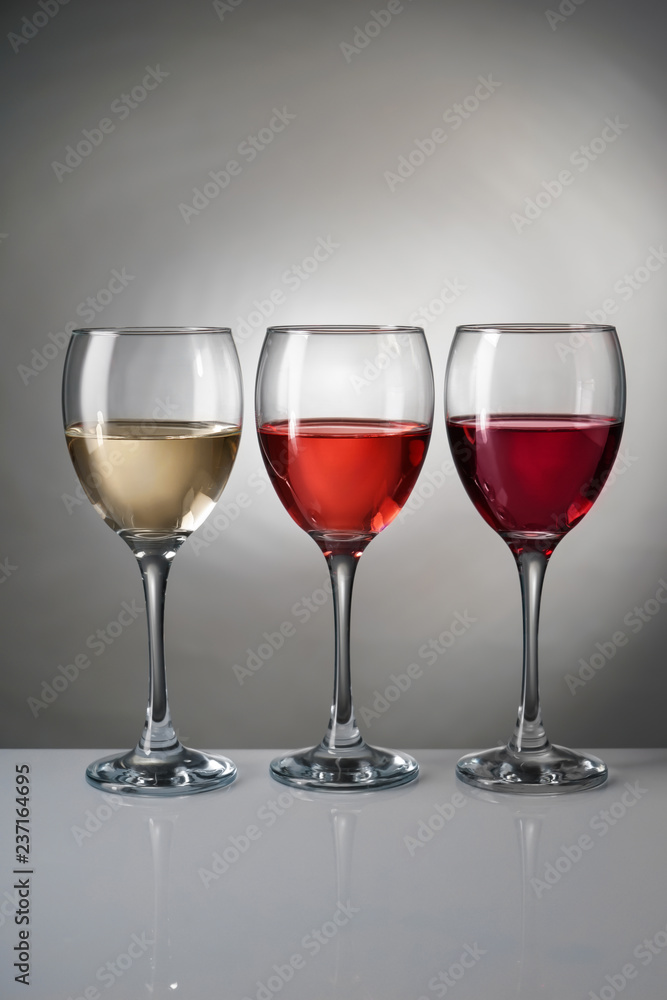 Glasses with different kinds of wine on grey background