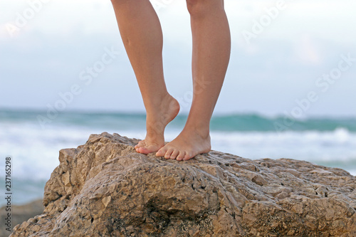 girl's legs against the background of the sea and the sand