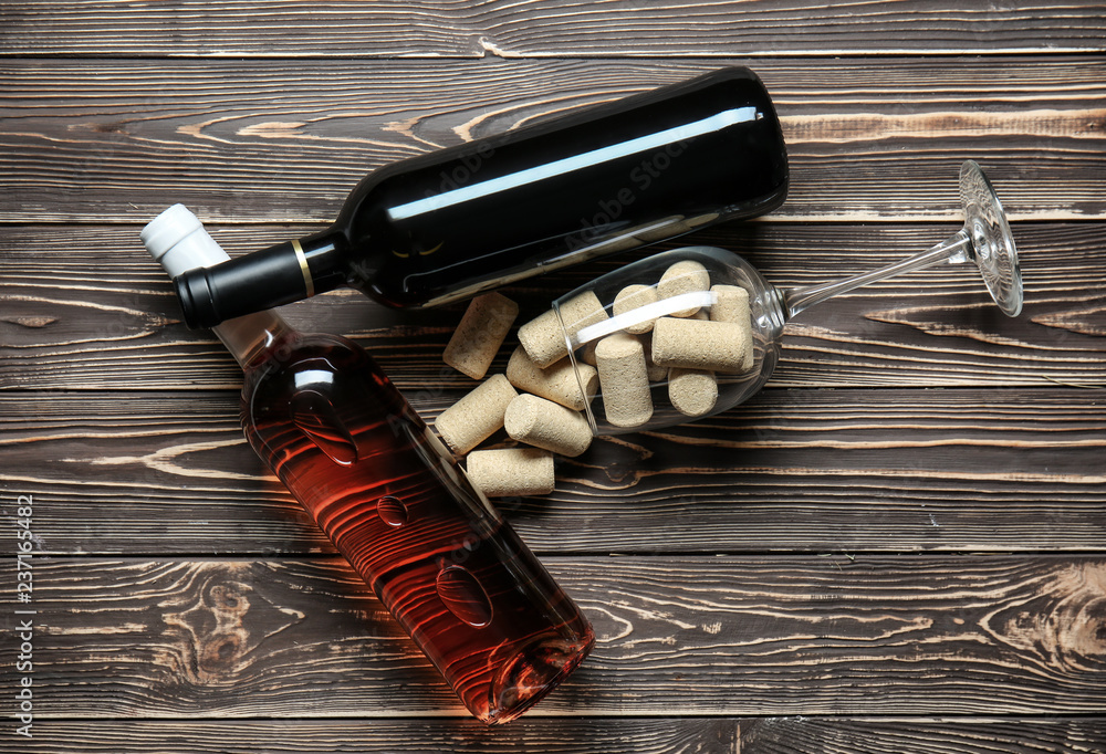 Bottles with different kinds of wine and corks on wooden background