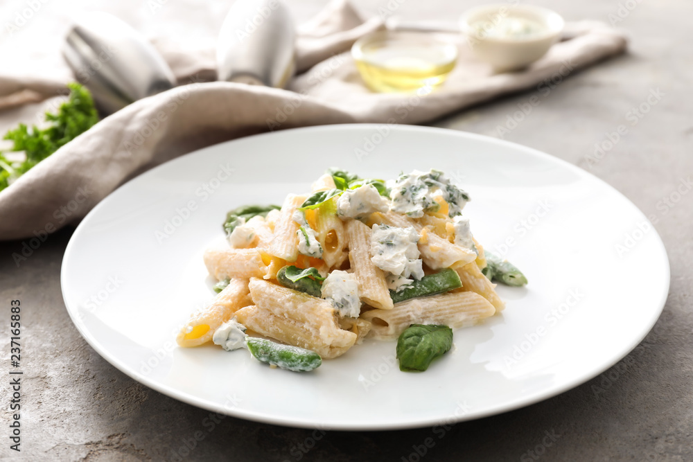 Plate with tasty penne pasta on grey table Plate with tasty penne pasta on grey table