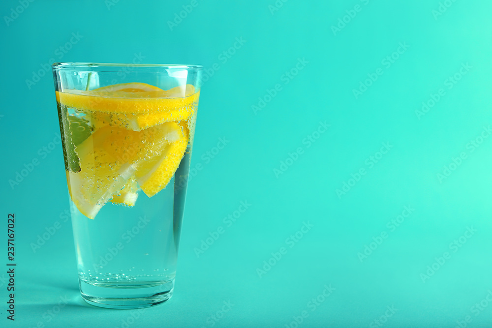 Glass of water with lemon on color background Glass of water with lemon on color background