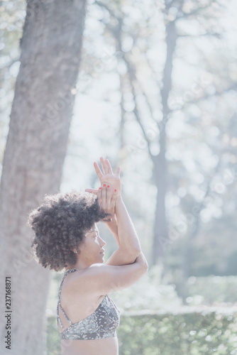 Afro woman practicing yoga in the city