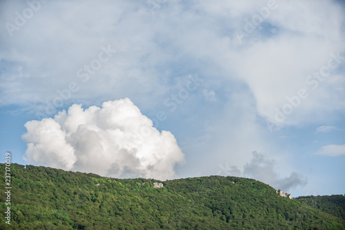 Wolkenbildung über bewaldetem und felsigen Berg photo