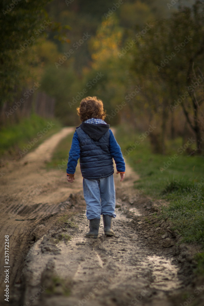 Little boy walkin on the muddy country road Little boy walkin on the muddy country road