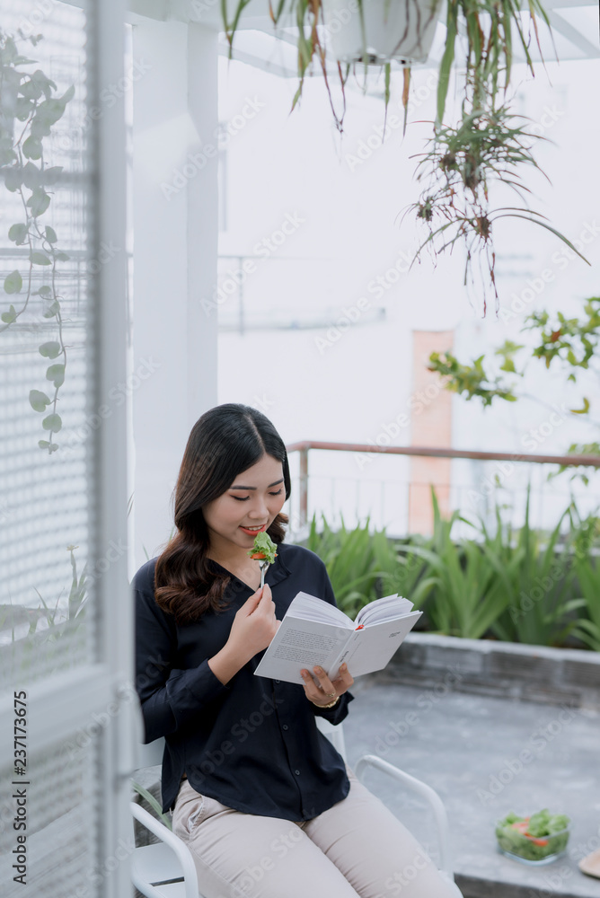 Fototapeta premium The beautiful girl in a summer cafe reading a book