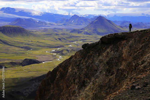 Travel to Iceland (northern Europe). Walk through the Landmannalaugar nature reserve, mountains, plains and volcanoes. A tourist is at the top of a hill.