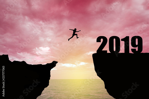 Man jumping 2019. man jumping over cliff on sunset background,Business concept idea