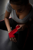 Thai transgender model in a Thai Box (Muay Thai) gym wrapping her hands with red handwraps bandages