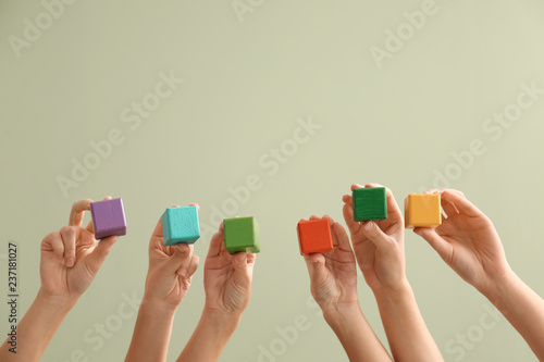 Young women holding cubes on color background