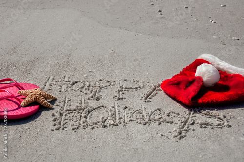 Wallpaper Mural Tropical Christmas at the beach, with happy holidays written in the sand, flip flops, a starfish and santa hat. Torontodigital.ca