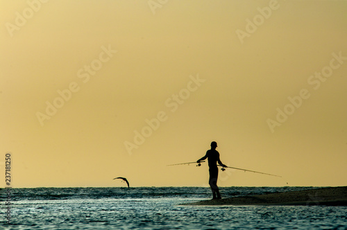 Wallpaper Mural A silhouetted man fishes at sunset along Barefoot Beach, Florida. Torontodigital.ca