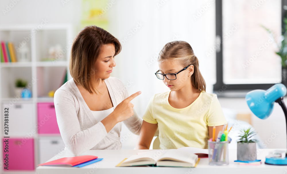 education, family and learning concept - strict mother talking to daughter while doing homework at home education, family and learning concept - strict mother talking to daughter while doing homework at home