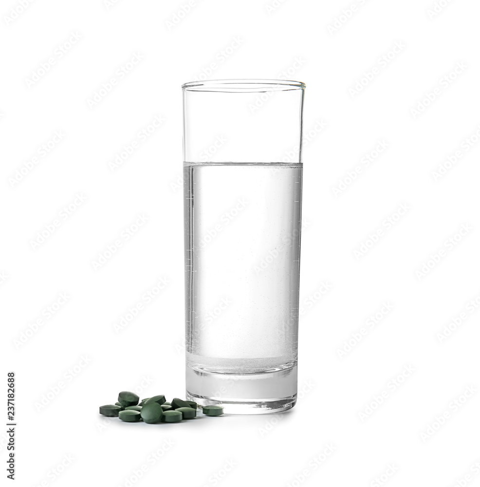 Glass of water with spirulina tablets on white background Glass of water with spirulina tablets on white background