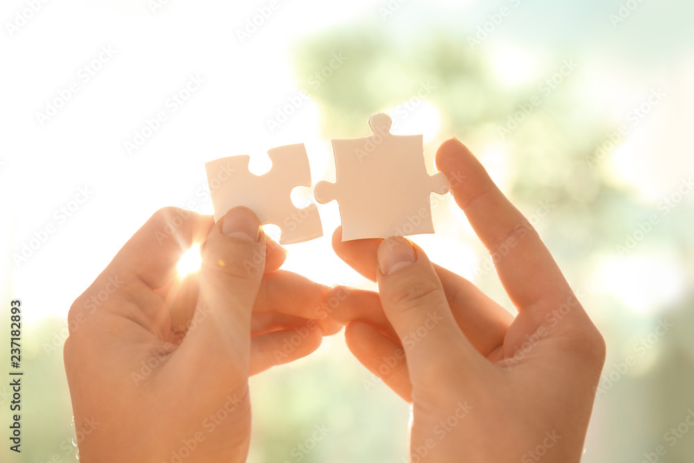 Woman with pieces of puzzle near window on sunny day, closeup Woman with pieces of puzzle near window on sunny day, closeup
