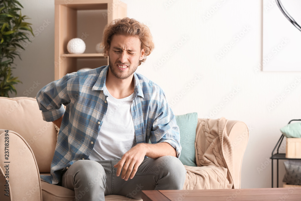 Young man suffering from back pain at home Young man suffering from back pain at home