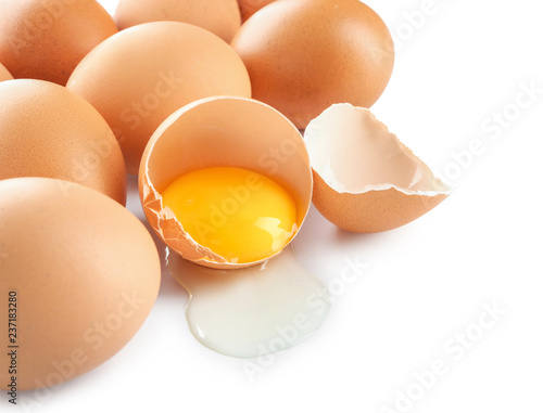 Cracked and whole chicken eggs on white background